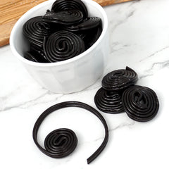 Broadway Black Licorice Wheels unrolled on a plate, highlighting chewy texture and bite-sized pieces.