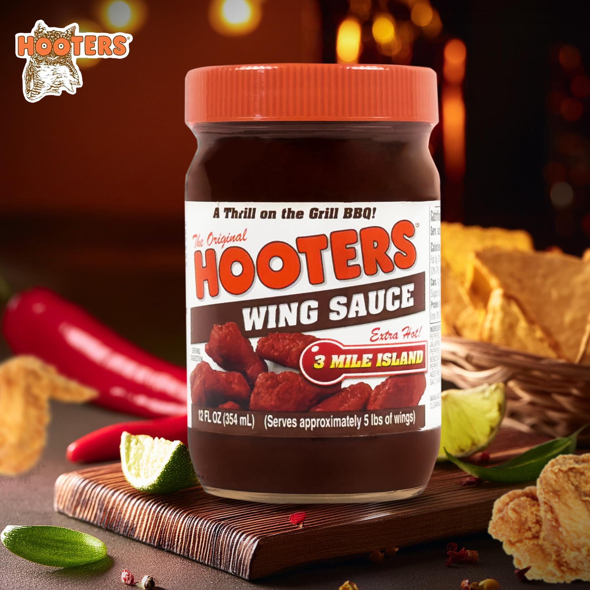 Pouring The Original Hooters 3 Mile Island sauce over wings for a spicy glaze.