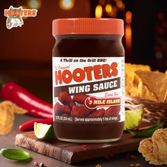 Pouring The Original Hooters 3 Mile Island sauce over wings for a spicy glaze.