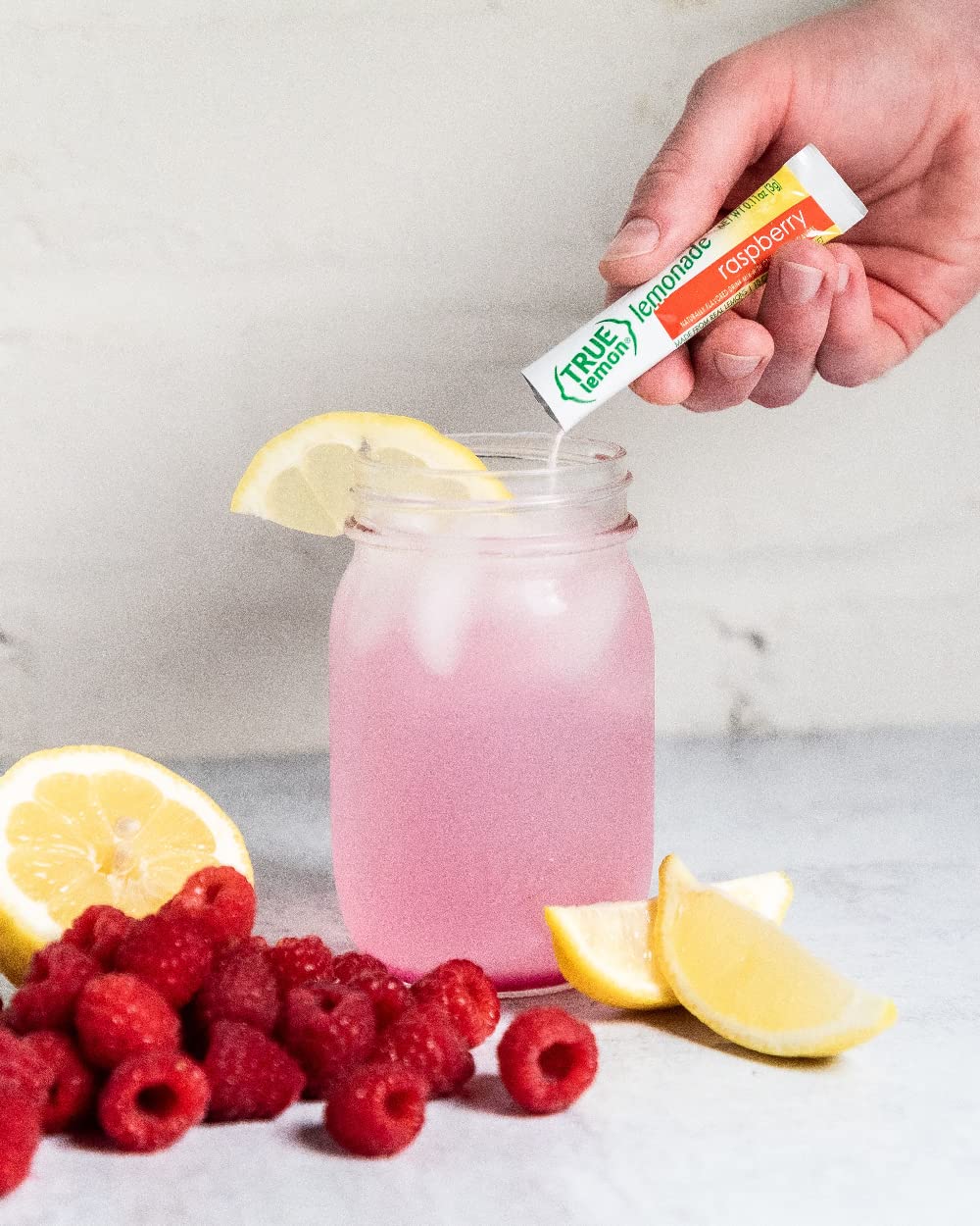 Chilled glass of raspberry lemon water with ice and berries.