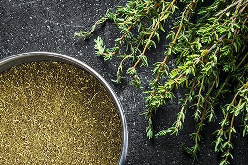Pouring Unpretentious ground thyme into a simmering soup for depth