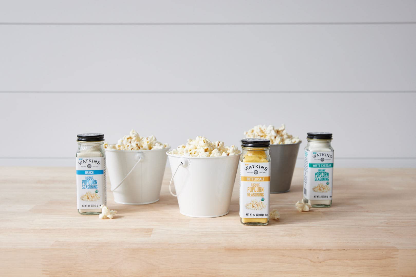 Watkins seasoning jar sits on a tidy kitchen counter beside popcorn.
