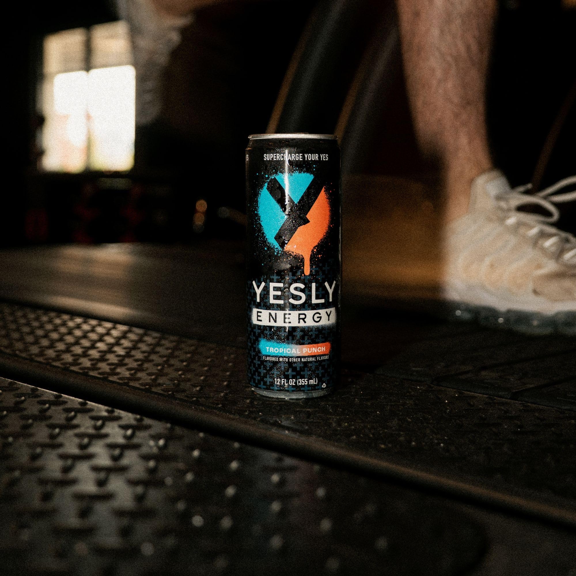 Yesly Energy Tropical Punch bottle with tropical fruits backdrop emphasizing flavor