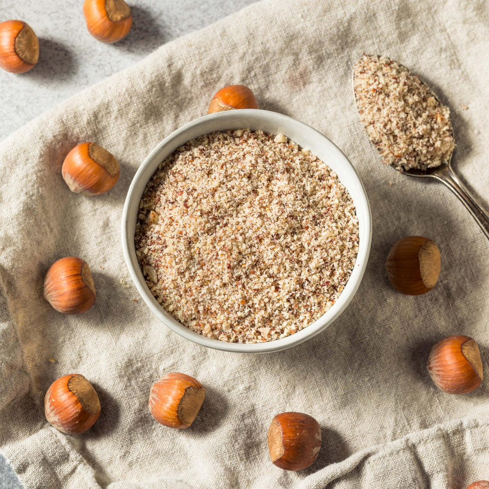 Raw hazelnuts beside milled meal showing natural ingredient source