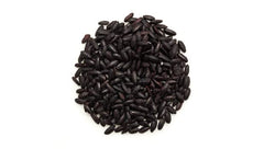 Yupik black rice grains beside fresh vegetables for salads or sides.