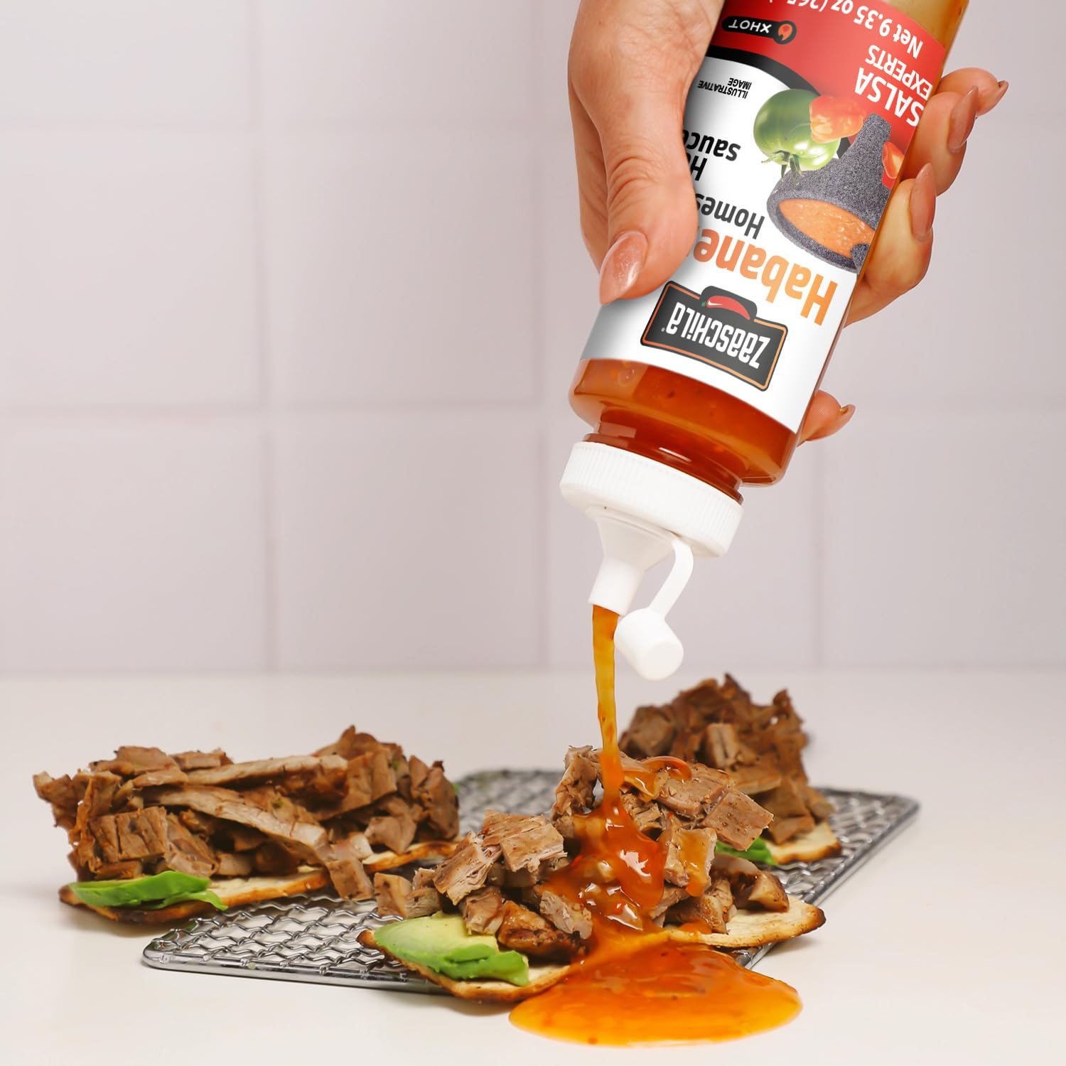 Spoon of Zaaschila sauce on tacos showcases bold heat.
